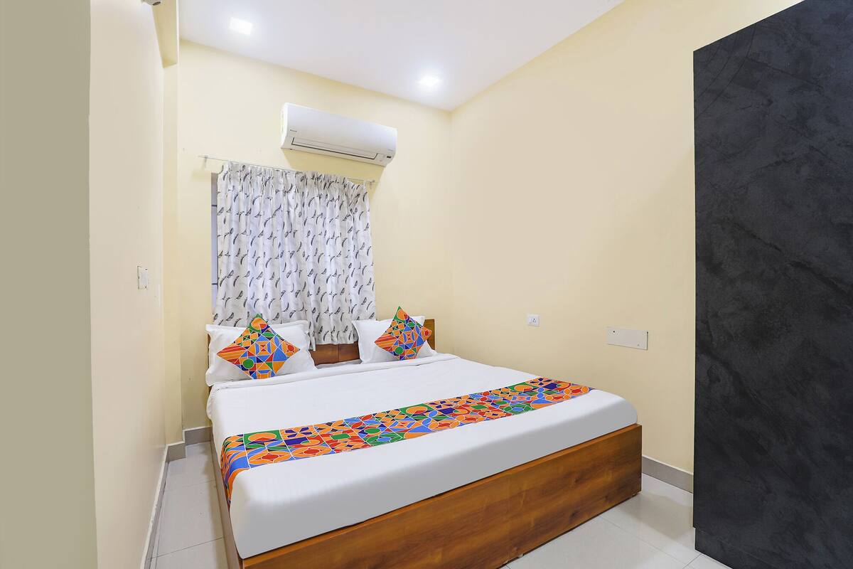 Un dormitorio con cama, cortinas y un aire acondicionado.