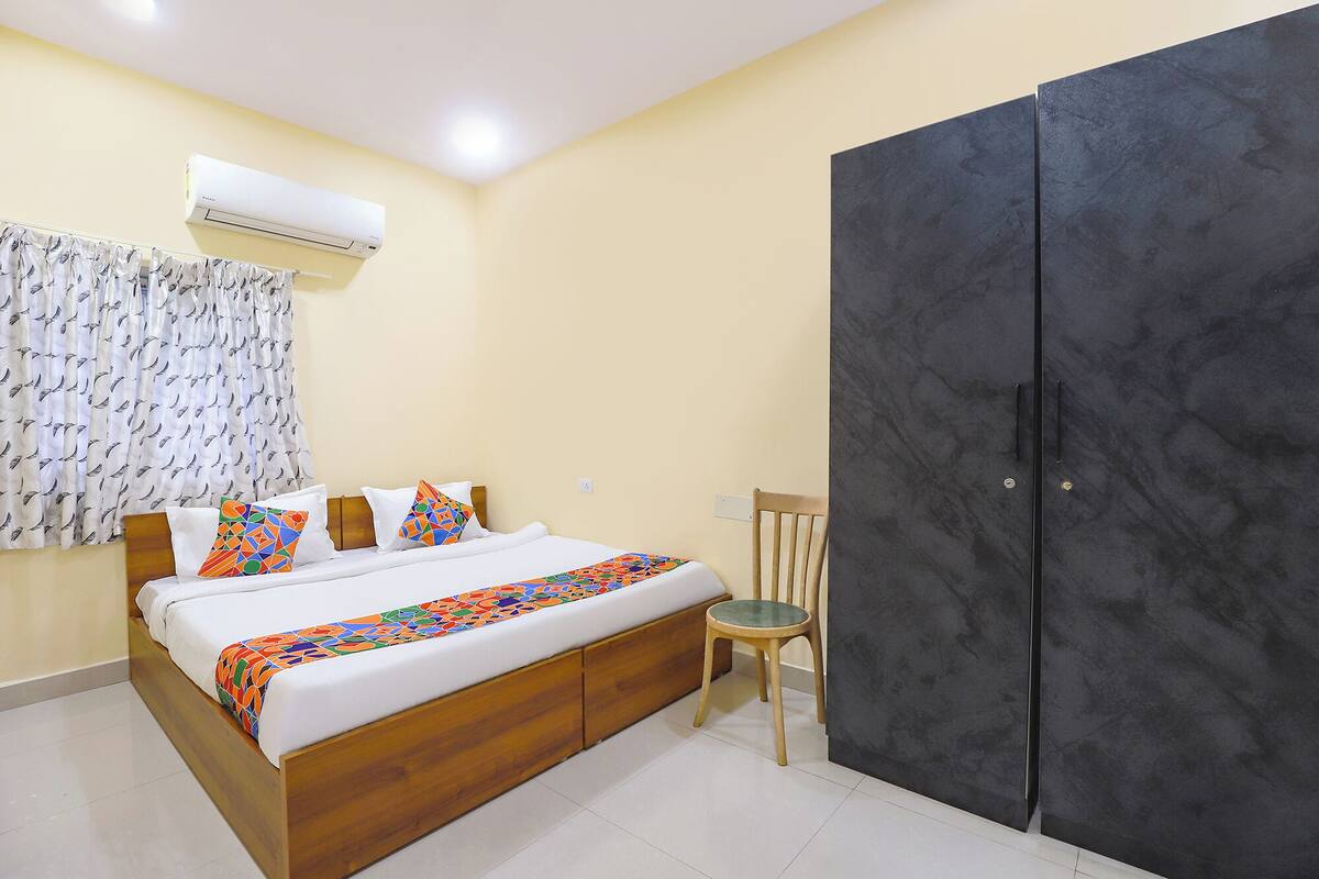 Un dormitorio con cama, una silla, un armario y un equipo de aire acondicionado.