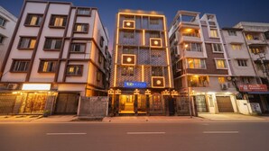 Ένα πολυώροφο ξενοδοχείο με μοντέρνα πρόσοψη, φωτεινές επιγραφές και μια πύλη στην είσοδο.