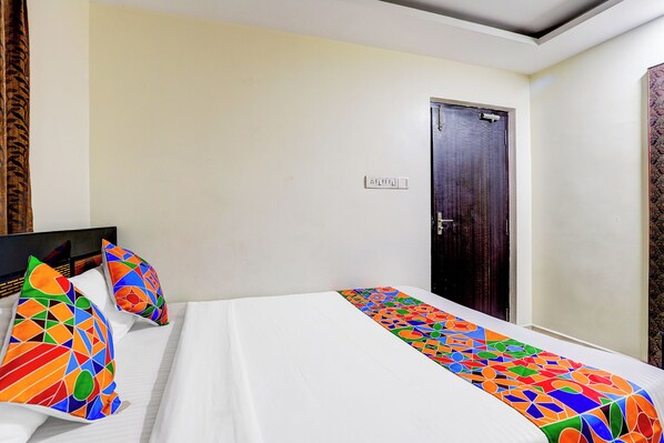 A hotel room with a bed, a TV, and a door. - FabExpress Karuna Regent (Chennai)