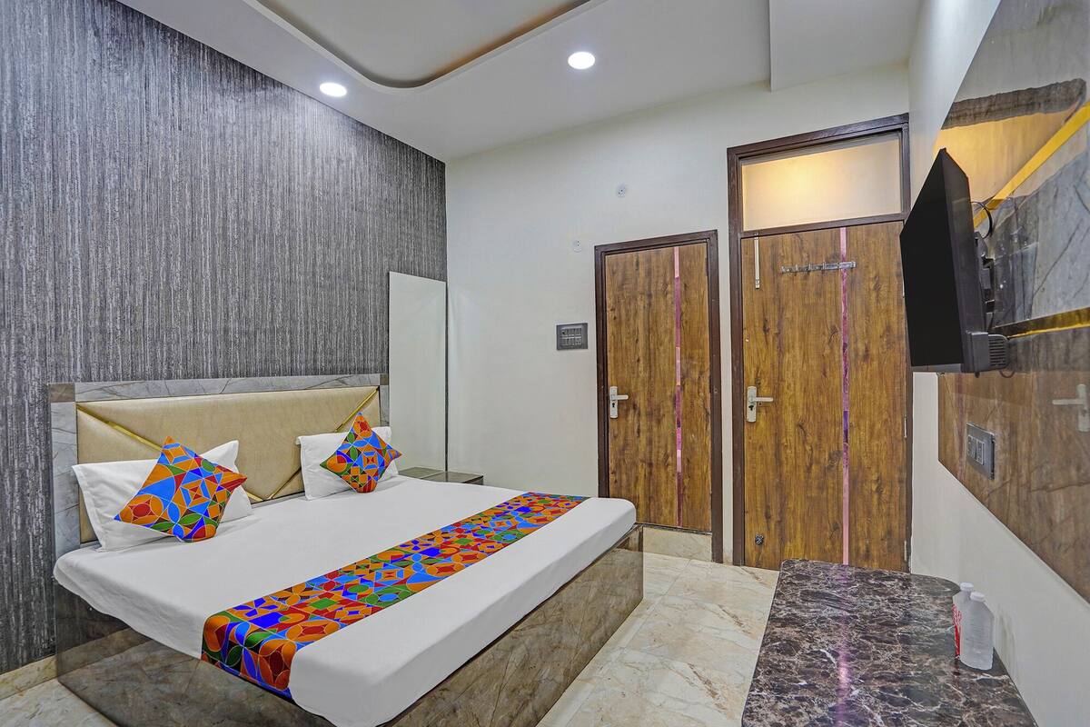 A modern hotel room with a bed, a small table, a TV, and a wardrobe.