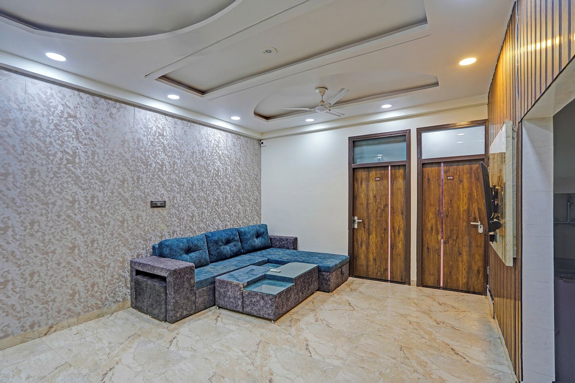 A modern room with a blue sectional sofa, a ceiling fan, and two wooden doors.
