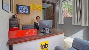 Een receptiebalie van een hotel met een computer, een televisiescherm waarop wild dieren te zien zijn, en een bordje met een rookverbod.