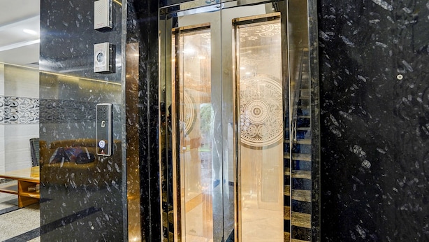 Un ascensor moderno con puertas de vidrio reflectante y un interior de mármol.