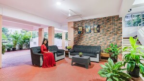 Um hall amplo com dois sofás, uma mesa de centro e plantas em vasos.