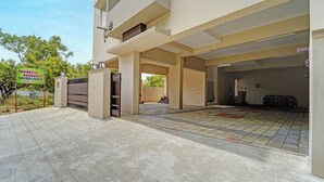 A residential building with a gated entrance, a covered parking area, and a sign indicating the availability of A/C and non-A/C rooms. - Fabhotel Praneeth Residency (Sulur)