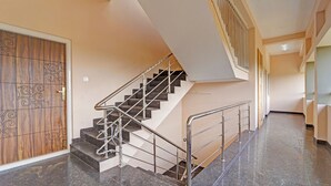 A staircase with metal railings and a wooden door with decorative patterns. - Fabhotel Praneeth Residency (Sulur)
