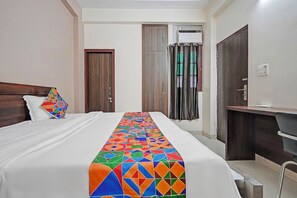 Quarto de hotel com uma cama, uma escrivaninha e um guarda-roupa.