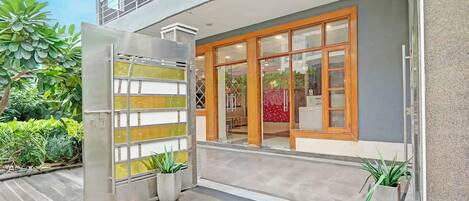 Un edificio moderno con puerta de vidrio, balcón y plantas en macetas.