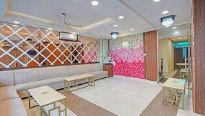 A modern hotel lobby with a seating area, a decorative wall, and a chandelier. - Fabhotel The Virat (Noida)