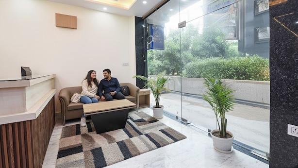 A modern hotel lobby with a reception desk, a seating area with a coffee table, and potted plants. - FabHotel Dwarka Heritage - Nr. Yashobhoomi Convention Centre (New Delhi)