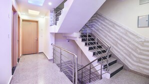 A modern interior with a staircase, a door labeled '105', and a security camera. - FabHotel Dwarka Heritage - Nr. Yashobhoomi Convention Centre (New Delhi)