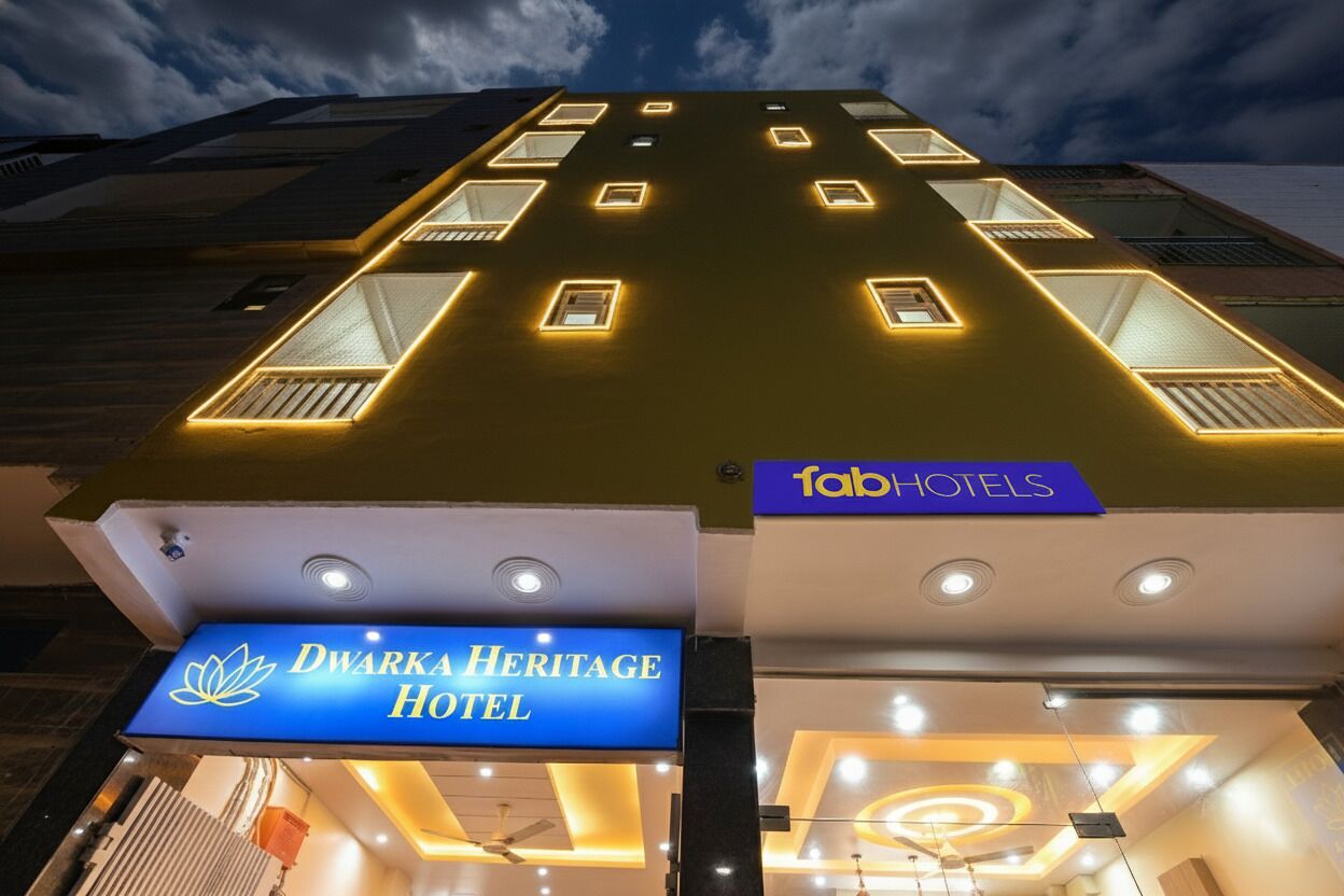 Exterior de l'Hotel Dwarka Heritage amb finestres il·luminades i un cartell de FabHotels.