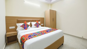 A neatly arranged hotel room with a wooden bed, a wardrobe, and a bedside table. - FabHotel Dwarka Heritage - Nr. Yashobhoomi Convention Centre (New Delhi)