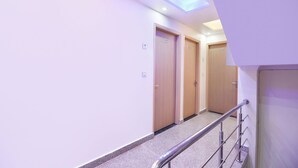 A modern hotel corridor with wooden doors, a metal handrail, and a skylight. - FabHotel Dwarka Heritage - Nr. Yashobhoomi Convention Centre (New Delhi)