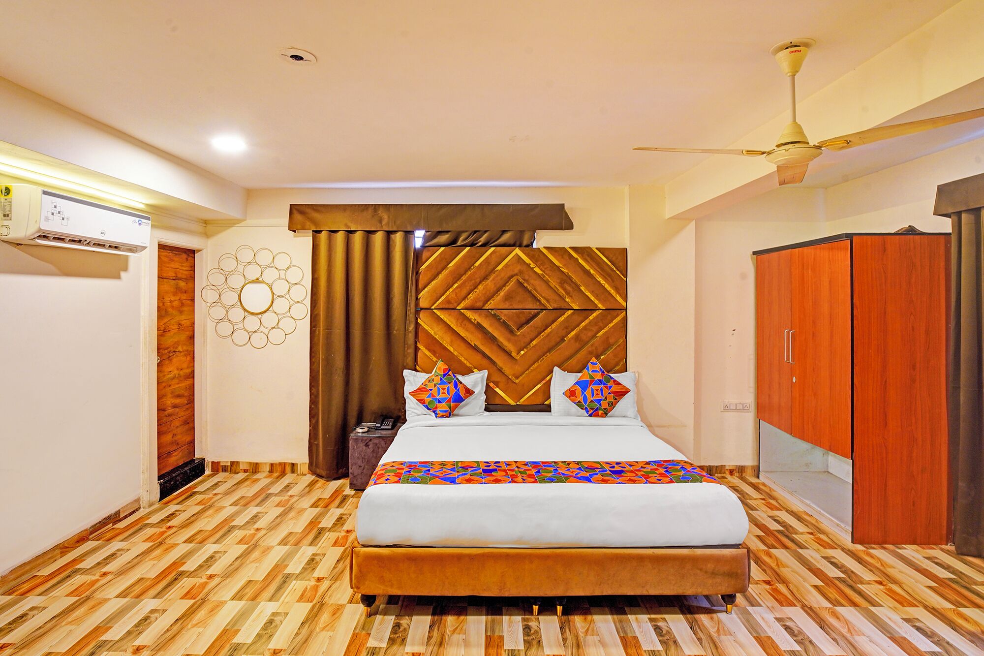 A bedroom with a bed, a ceiling fan, a wardrobe, and a wall-mounted air conditioning unit.