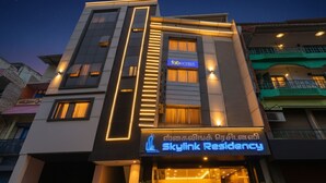 Ein modernes Hotel mit einem markanten Schild 'Skylink Residency', das eine elegante Fassade und beleuchtete Beschilderung zeigt.