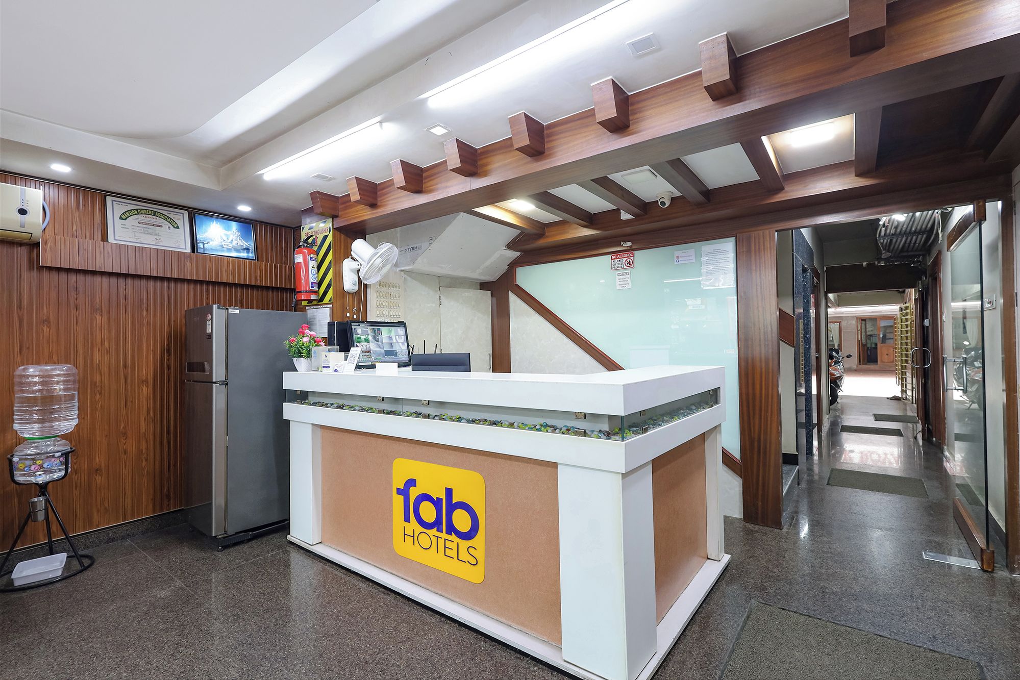 A reception desk with a 'fabo hotels' sign, a refrigerator, a water dispenser, and a fire extinguisher.