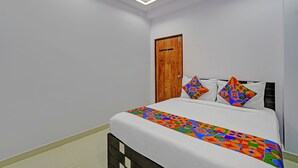 A bedroom with a bed, a wooden door, and a ceiling light fixture. - Fabhotel Wild Wings Ecil (Hyderabad)