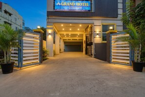 L’entrée du Grand Hôtel présente un design moderne, avec un chemin bien éclairé et une entrée fermée par un portail.