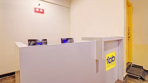 A reception desk with a 'fab hotels' logo, a clock indicating 11 AM and 12 PM, and a door to the right. - Fabhotel Platinum (Bengaluru)