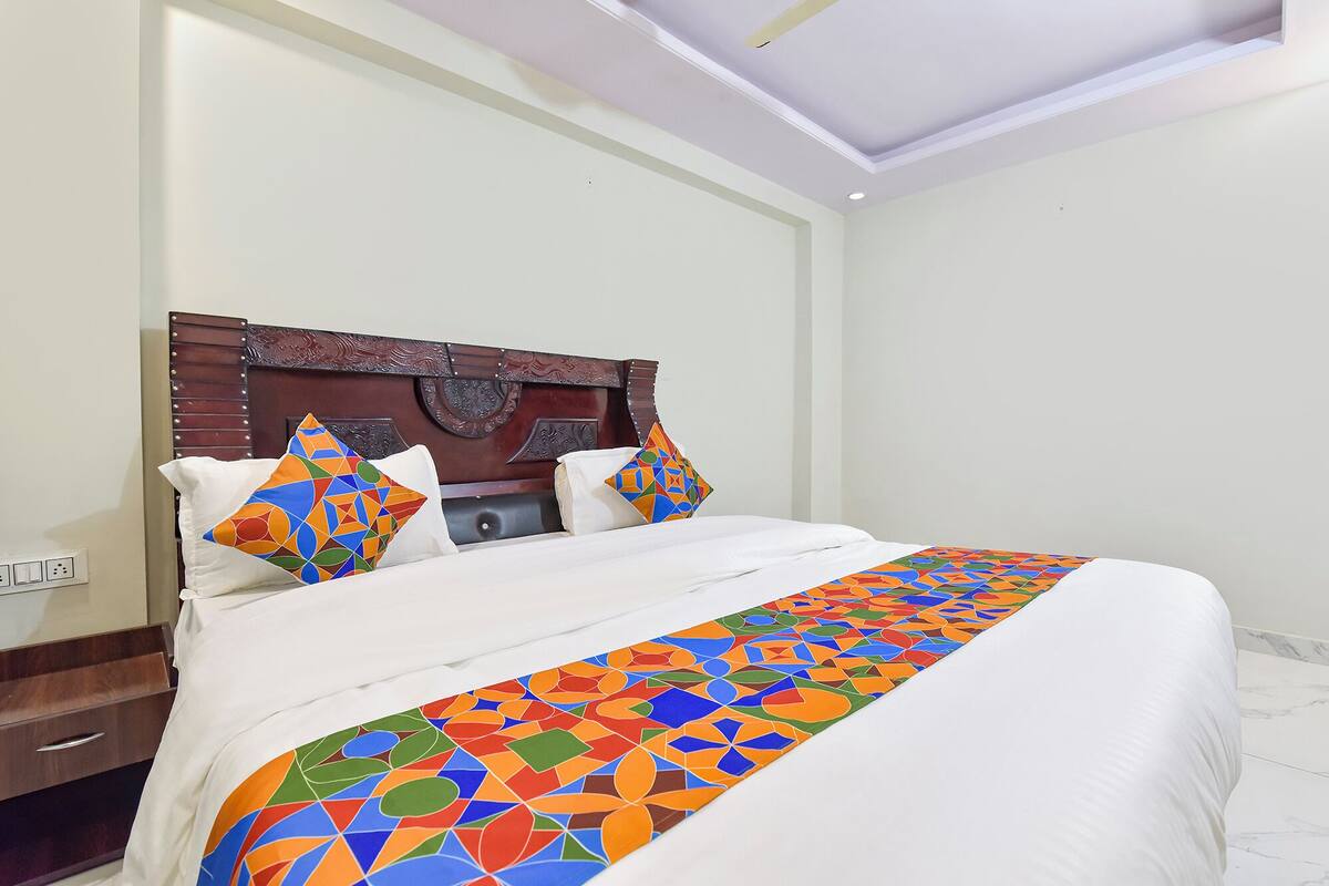 A neatly made bed with a colorful geometric-patterned bedspread, a wooden headboard, and two decorative pillows.