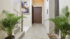 A hallway with a marble floor, a wooden door, and two potted plants. - Fabhotel Bungalow 14 (Jaipur)