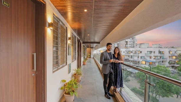 Un balcón con barandillas de madera, plantas en macetas y vistas a la ciudad.