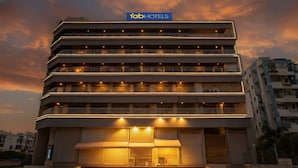 Un hotel de varios pisos con fachada plana, ventanas iluminadas y un cartel con el nombre "fabHOTELS" en la parte superior.