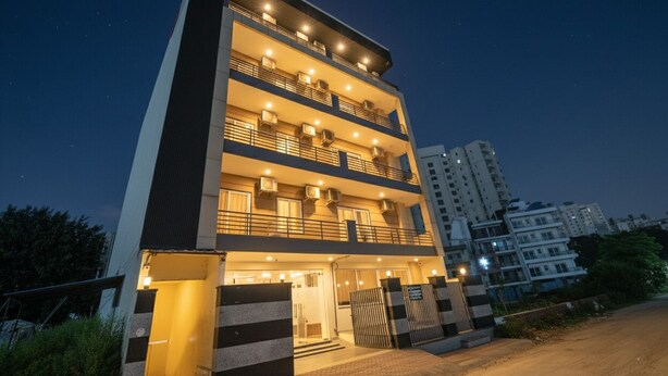 A multi-story building with balconies, a gated entrance, and a well-lit facade at night. - Fabhotel Alpha Stayz (Gurugram)