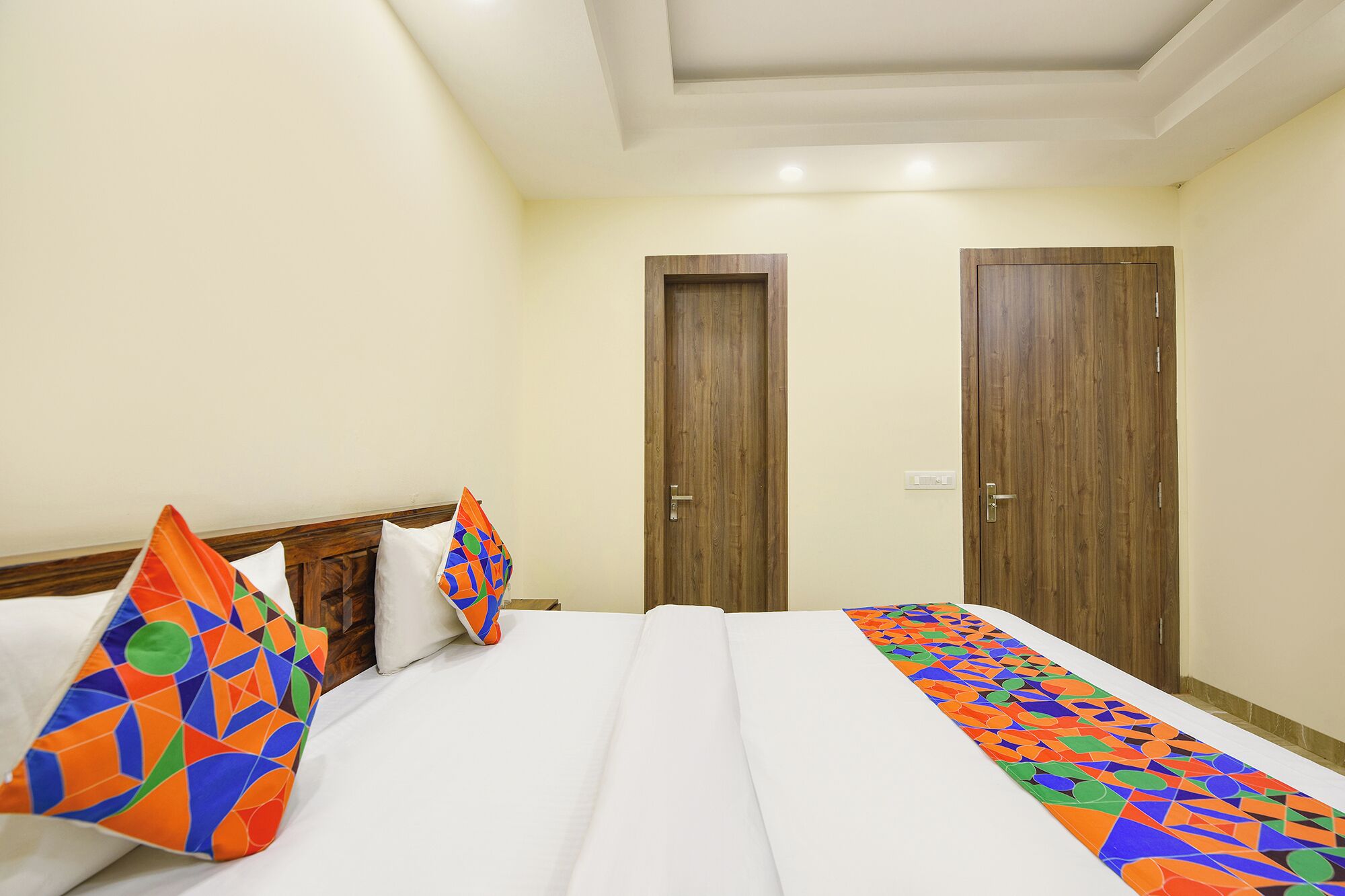 A hotel room with a bed, two doors, and a white ceiling.
