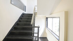 A staircase with a metal handrail and a window on the right side. - Fabhotel Alpha Stayz (Gurugram)