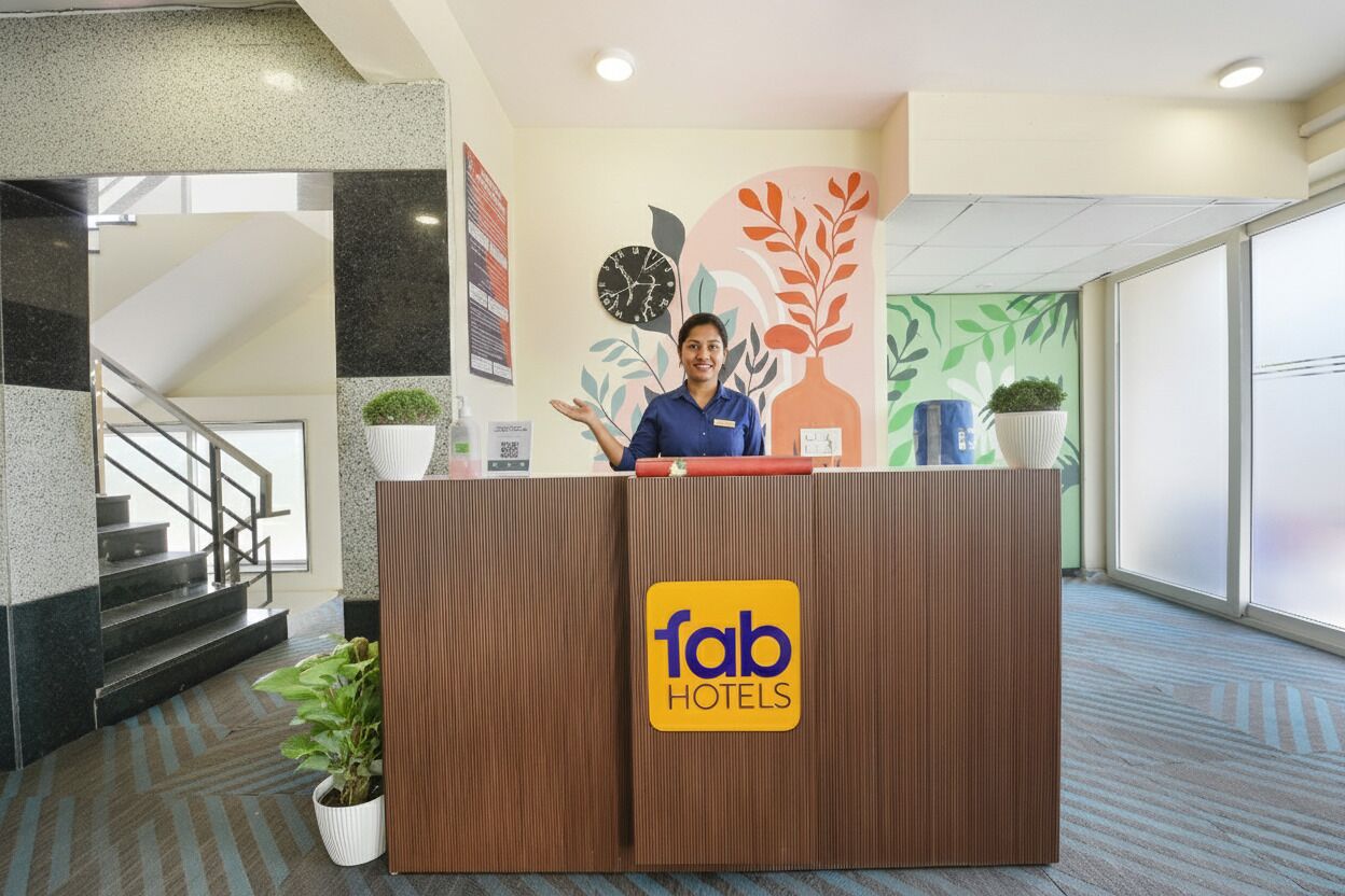 Un comptoir d’accueil orné du logo de « fab hotels » et agrémenté d’une plante sur la gauche.