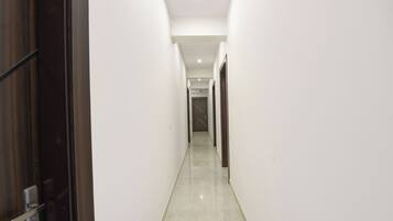 A narrow, well-lit hallway with a polished floor, leading to a door at the end.