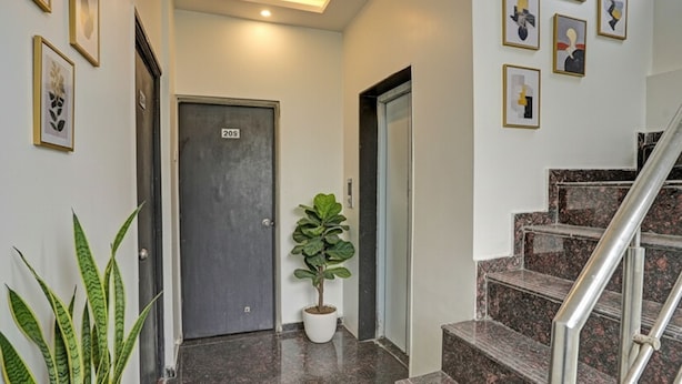 A hotel lobby with a marble staircase, a potted plant, and framed artwork on the walls. - Fabhotel Royal Inn I (Pune)