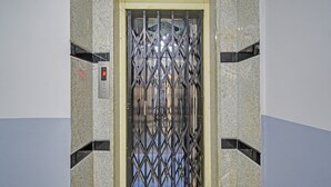 An elevator with a metal gate and a digital display showing the number 3. - Fabhotel Smart (Hyderabad)