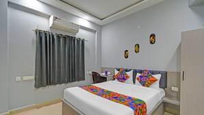 A hotel room with a bed, a desk, an air conditioner, and a wardrobe. - Fabhotel Smart (Hyderabad)