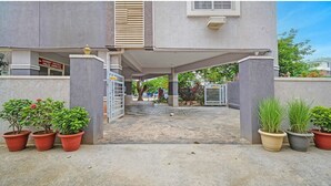 A building entrance with a covered walkway, potted plants, and a sign for a sports facility. - Fabhotel Smart (Hyderabad)