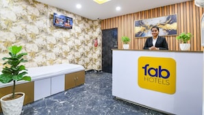 A reception area with a marble wall, wooden paneling, and a reception desk with a logo. - Fabhotel Top 22 (Kolkata)