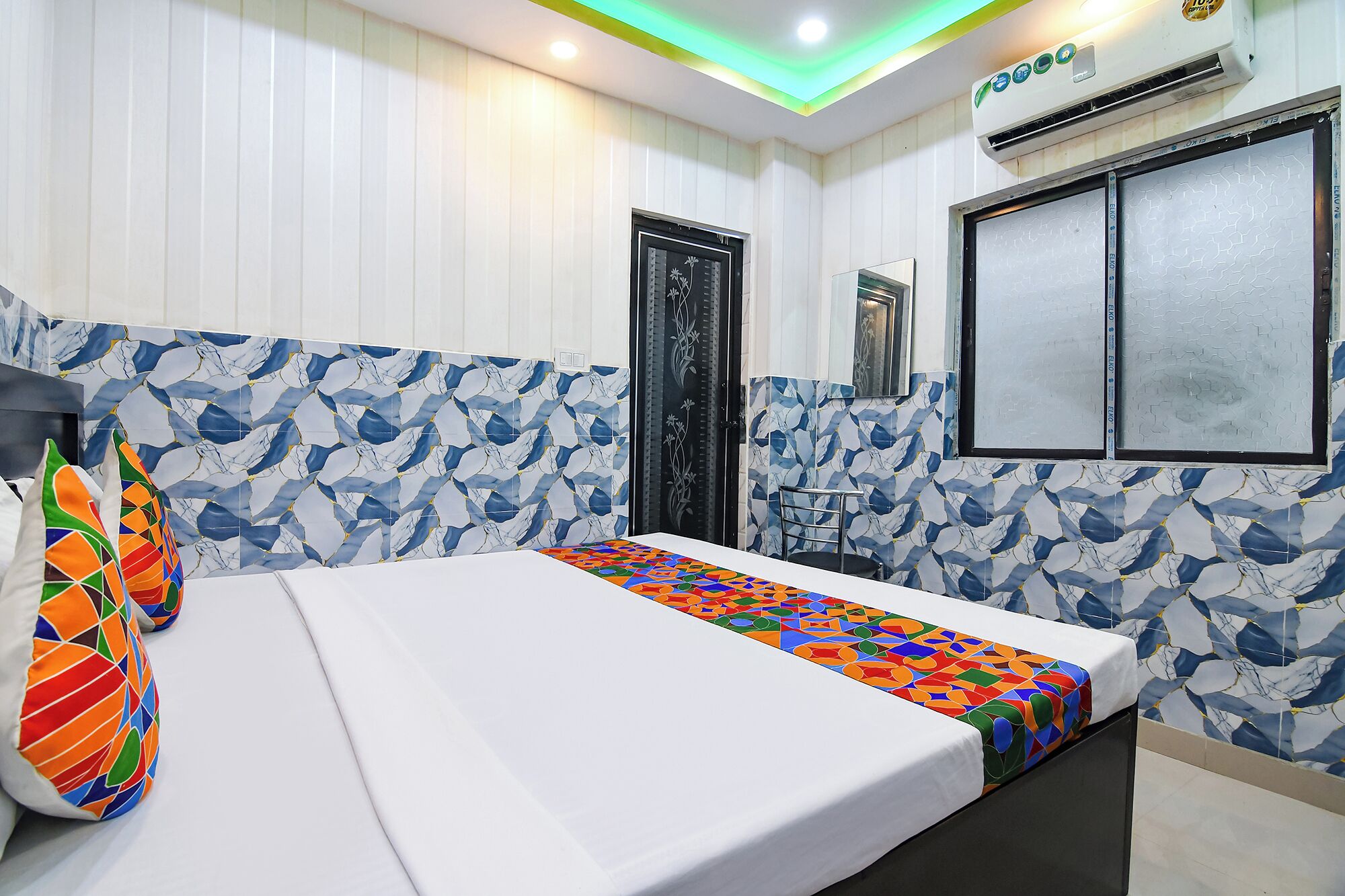 A hotel room with a bed, a window with a view, and a wall with a geometric pattern.