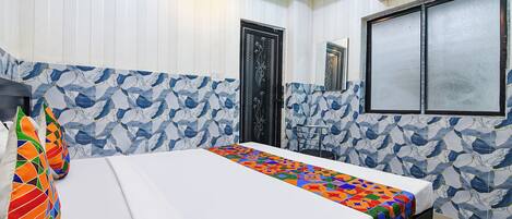 A hotel room with a bed, a window with a view, and a wall with a geometric pattern.