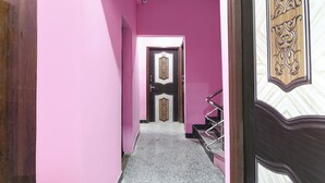 A narrow hallway with pink walls and a wooden door with intricate designs. - Fabhotel Top 22 (Kolkata)