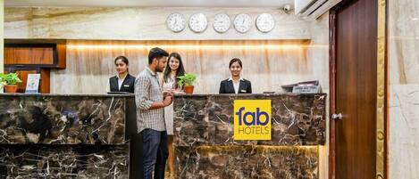 A reception desk with a marble design, a clock, and a sign for Fab Hotels.