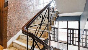 Un escalier en marbre, agrémenté de rampes en métal noir, et offrant une vue sur l’extérieur grâce à de grandes fenêtres.