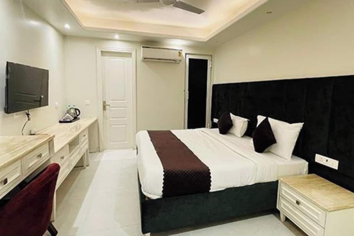Une chambre d’hôtel équipée d’un lit, d’une table de chevet, d’une télévision, d’un bureau, d’une chaise et d’un ventilateur de plafond.