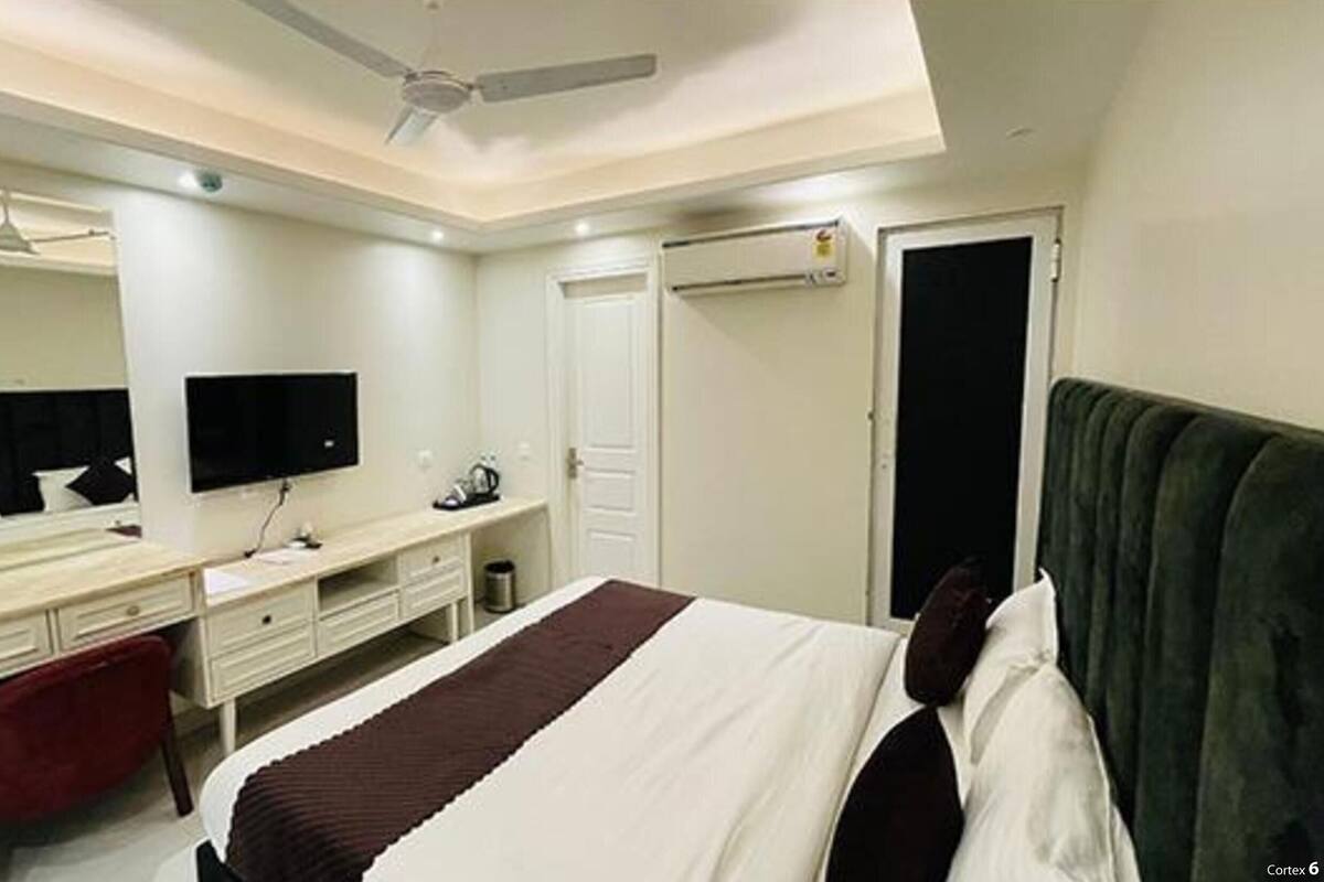 Une chambre d’hôtel comprenant un lit, un bureau, une chaise, une télévision et une armoire.