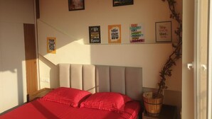 A bedroom with a bed, a headboard, a wall-mounted shelf with motivational posters, and a small plant. - Peaceful Escape (Zirakpur)