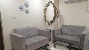 A living room with two grey sofas, a glass coffee table, and a decorative wreath on the wall. - Peaceful Escape (Zirakpur)