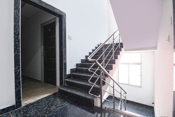 A staircase with metal railings leading to a landing. - Fabhotel Westin Regency (Shrirampur)