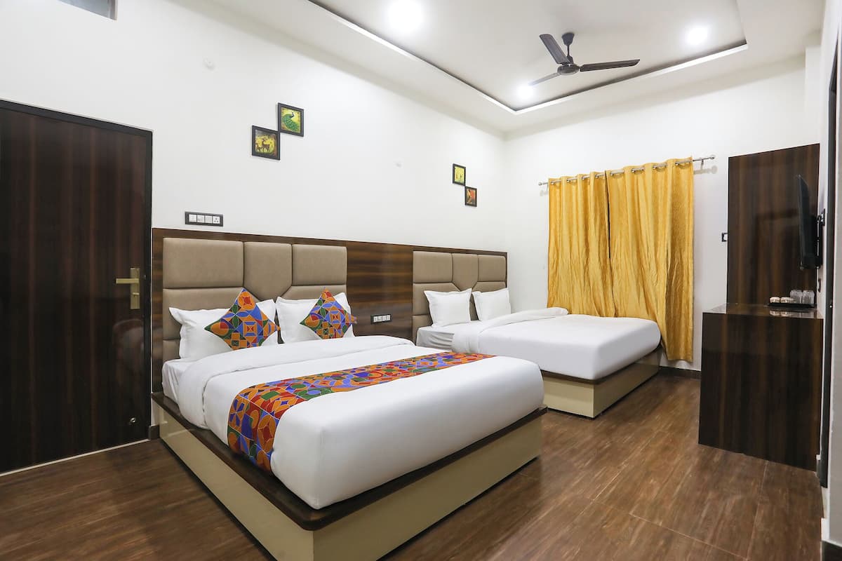 A hotel room with two beds, a ceiling fan, and a large window with curtains.